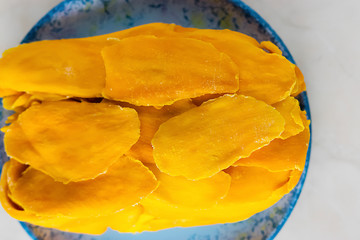 Sun-dried mango slices on a blue plate close-up.