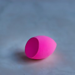 Pink cosmetic sponge on a light background.