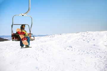 Fototapeta na wymiar Man using chairlift at mountain ski resort, space for text. Winter vacation