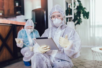 Specialists in protective suits do disinfection or pest control in the apartment.
