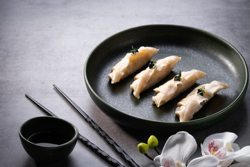 Japanese gyoza dumplings on grey stone table background. Traditional asian food. Cooked dim sum with salmon, soy sauce and chopsticks. Copy space, close up