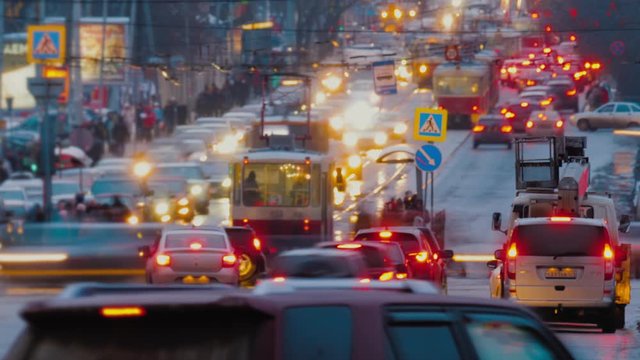 Timelapse: big city traffic jam at evening. Cars is driving along busy street, tram station with walking people.