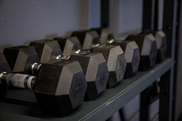 Naklejka na ściany i meble Close up many metal dumbbells on rack in sport fitness center. Weight Training Equipment concept. Sport and fitness, exercise design.