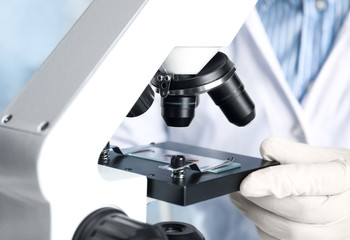 Scientist using microscope in laboratory, closeup. Virus research