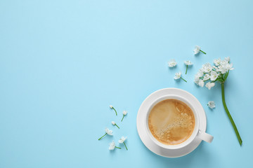 White flowers and coffee on light blue background, flat lay with space for text. Good morning
