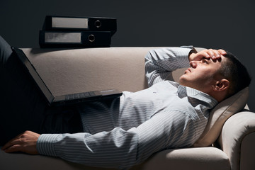 Obraz premium businessman is lying on the sofa with laptop and resting