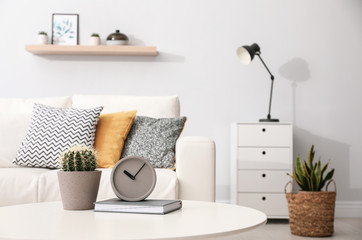 Clock and cactus on white table in stylish living room