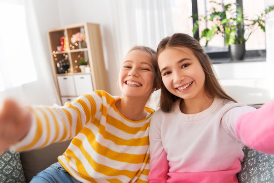 people and friendship concept - happy smiling teenage girls taking selfie at home