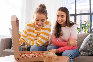 people, food and friendship concept - happy teenage girls eating takeaway pizza at home