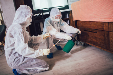 Specialists in protective suits do disinfection or pest control in the apartment.