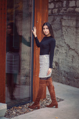 Beautiful woman with long black hair standing near the large windows and looking at the camera