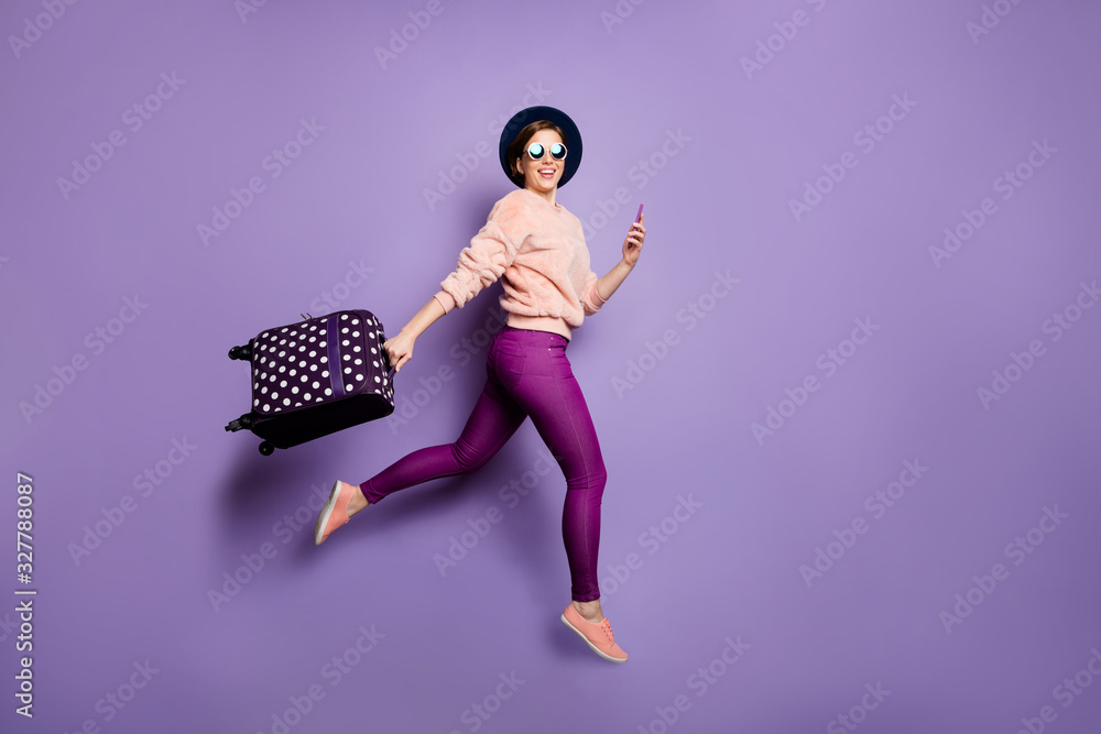 Sticker Tourism concept. Full body photo of funny lady jumping up rush airport hold telephone carry luggage wear cap glasses trendy pink pullover trousers isolated purple color background