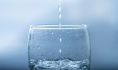 Pour drinking water into the glass with copy space