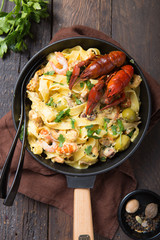 Seafood fettuccine pasta with crayfishes, octopus shrims, on stone pan. Gourmet dish