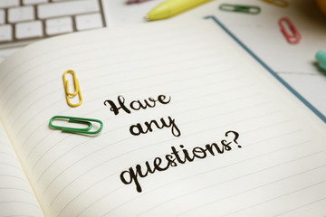 Obraz premium Notebook with phrase HAVE ANY QUESTIONS and stationery on table, closeup