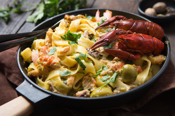 Seafood fettuccine pasta with crayfishes, octopus shrims, on stone pan. Gourmet dish