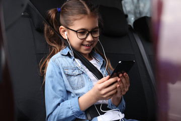 Cute little girl listening to audiobook in car