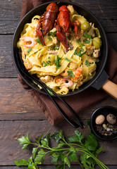 Seafood fettuccine pasta with crayfishes, octopus shrimps, on stone pan. Gourmet dish