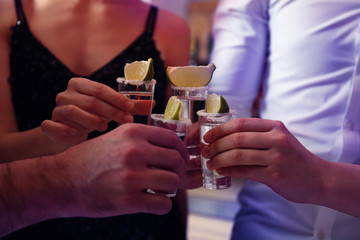 Young people toasting with Mexican Tequila shots in bar, closeup