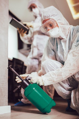 Specialists in protective suits do disinfection or pest control in the apartment.