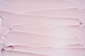 Gently pink brush strokes and texture of face cream or pink acrylic paint on a white background