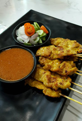Pork Satay with Peanut Sauce serving with pickles which are cucumber slices and onions in vinegar