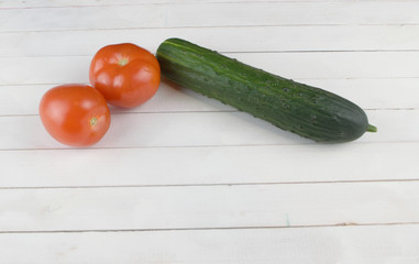 two tomatoes and a cucumber lie on the table