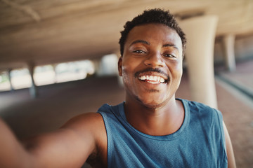 Portrait of a smiling young african american man taking selfie after jogging at outdoors
