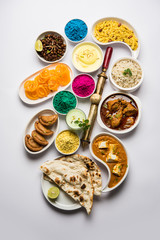 Fototapeta na wymiar Happy Holy concept showing Indian assorted lunch food like chicken, paneer butter masala, naan, jeera rice, black chana fry, jalebi, fujiyama, thandai and Farsan with holi colours and pichkari 