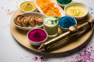 Happy Holy concept  showing Indian assorted sweets like jalebi, gujiya, than, ras malai with holi colours and pichkari, isolated over white background