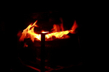 The embers on the stove that are burning are isolated against a black background, out of focus and...