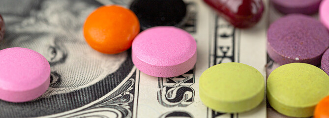 The concept of making money on medicines. Multicolored drugs on a background of dollars. Different...