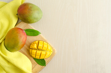flat lay ripe juicy mango on yellow background. slice and whole exotic fruit on wooden board. copy...