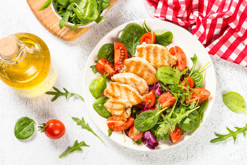 Grilled chicken with fresh salad on white.