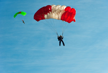 Skydivers with colorful parachutes in the sky.