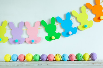 Colorful Easter eggs and handmade bunny easter garland on beige background.