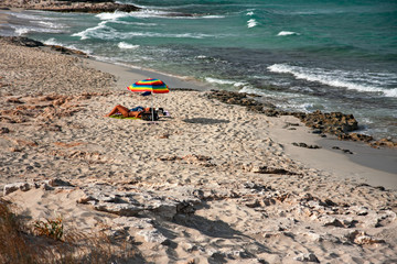 Bathers sunbathing in the wild and sunny Illetes beaches in Formentera on the Balearic islands of Spain.