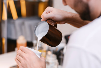 Fototapeta na wymiar Unrecognizable Barista Making Cappuccino Adding Milk In Cup In Cafeteria