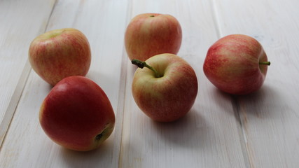 red garden apples scattered on a white shabby table