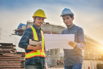 Contractor employee two people holding paperwork planing in building construction site and Use Hard hat safety protect in work