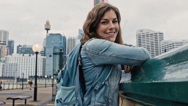 Alluring woman with eyes cast down looks directly into the camera with the Sydney skyline in the background. 