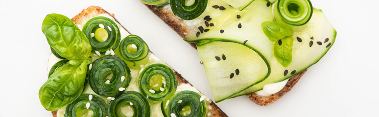 top view of fresh cucumber toasts with seeds and basil leaves isolated on white, panoramic shot