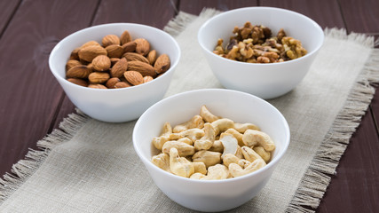 diet food concept, almonds, walnuts and cashew nuts on a wooden table