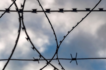 Barbed wire fence against the sky on a spring day, closeup photo