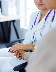 Woman doctor helping senior holding hand in hospital