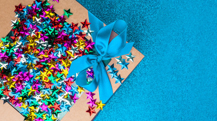 Obraz na płótnie Canvas craft gift box with satin blue bow and colorful stars