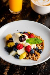 Granola, yogurt and fresh fruit. Traditional classic American restaurant or French bistro favorite menu item. Crunchy granola, yogurt, blueberries, strawberries, topped with mint
