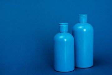 plastic bottles with shampoo on blue background with copy space
