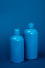 plastic bottles with shampoo on blue background with copy space