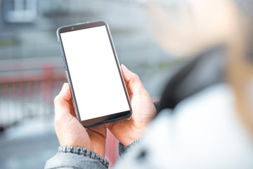 Hand holds a smartphone with a white screen. Blank mobile phone mockup